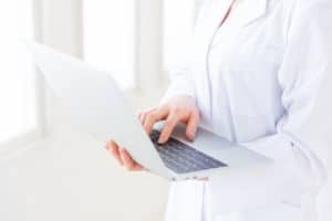 Medical professional working on laptop while doing rounds