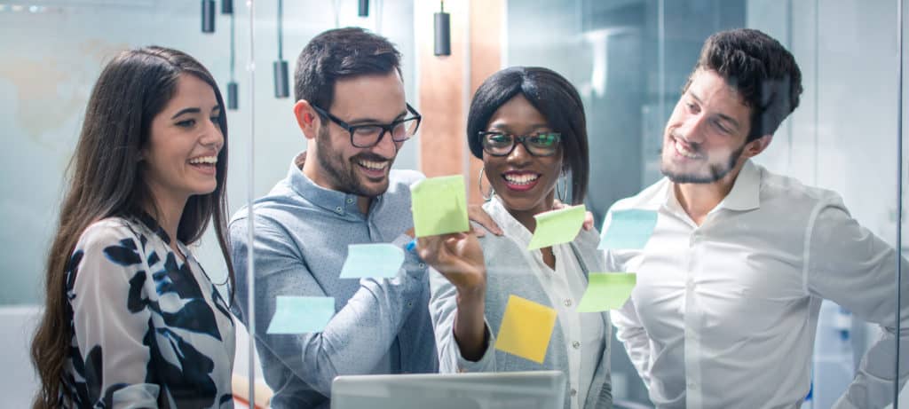 Panoramic view creative group of business people working with sticky notes on glass wall in office