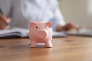 Crop close up of piggy bank on wooden table in hospital or private clinic for monetary donation, piggybank on desk for voluntary money contribution or charity for patient need care, volunteer concept