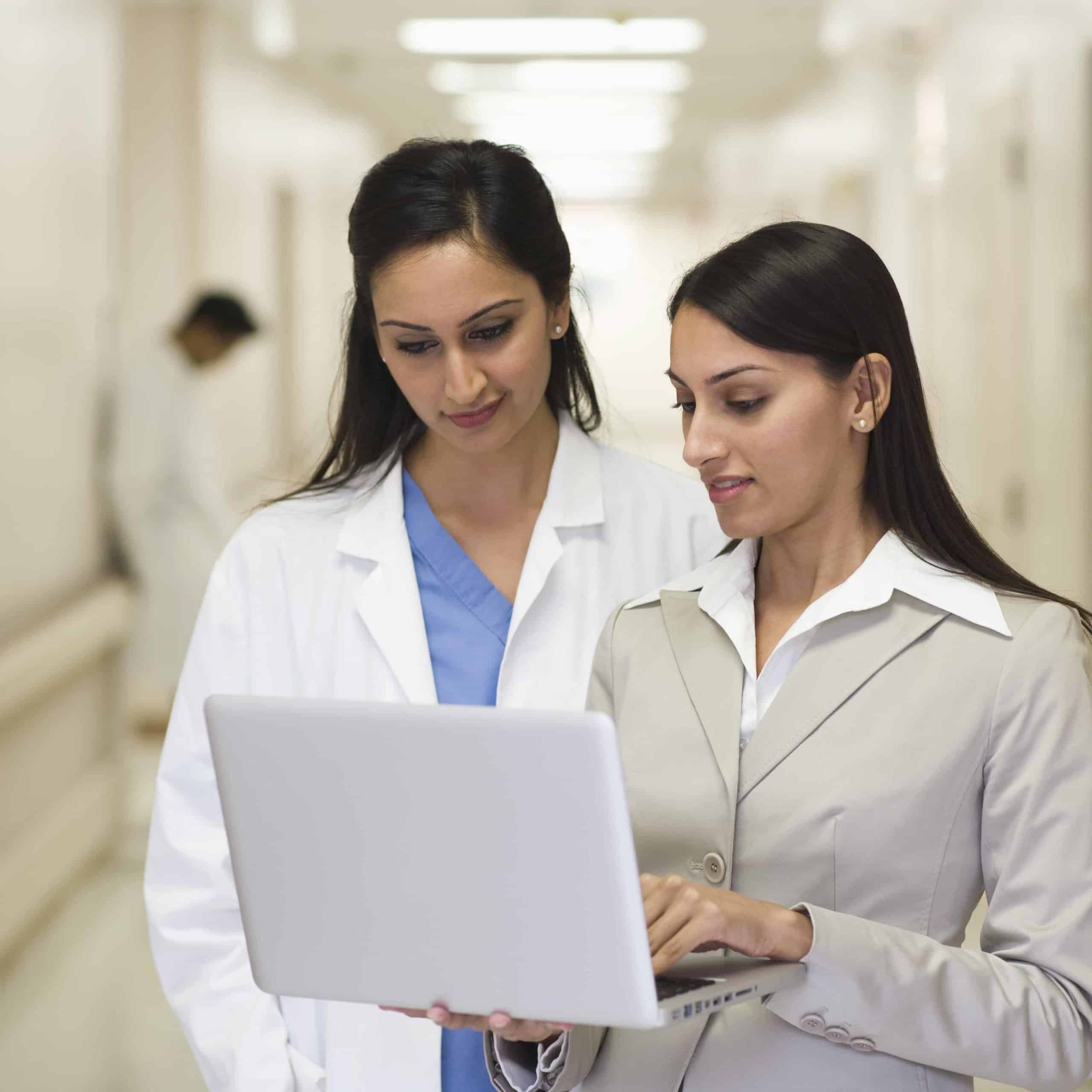 Businesswoman showing laptop to doctor in hospital